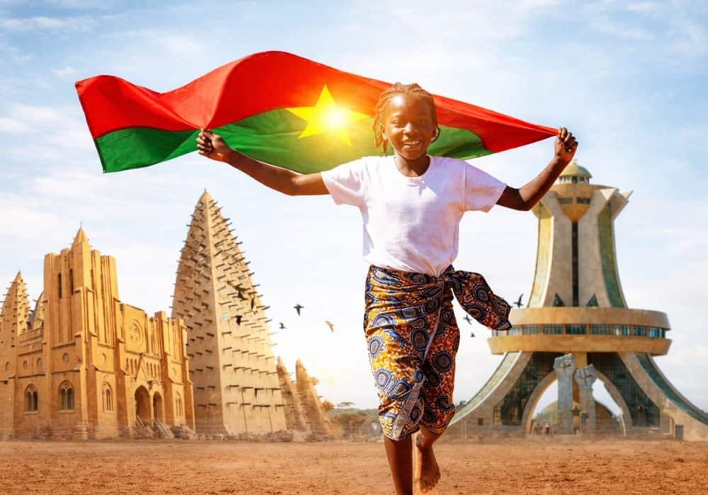 Jeune fille souriante tenant le drapeau du Burkina Faso.